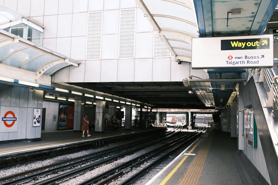 The image shows the entrance to Hammersmith underground station, with three railway tracks running into the station platform under a large, curved, semi-transparent canopy that allows natural light to