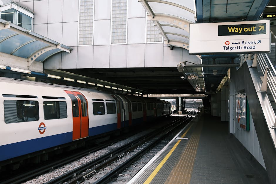The image shows the entrance to Hammersmith underground station, with three railway tracks running into the station platform under a large, curved, semi-transparent canopy that allows natural light to